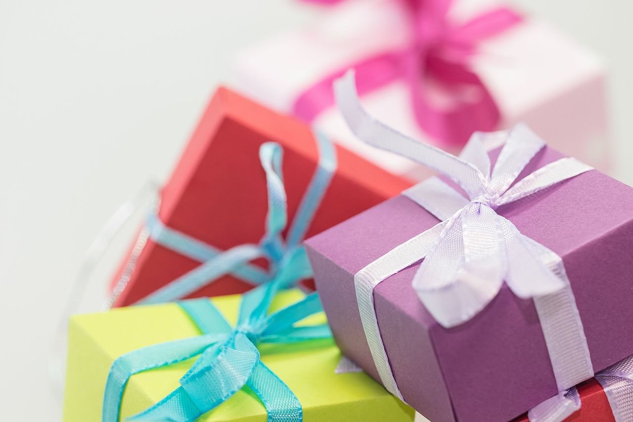 Small gift boxes in purple, red, green and pink, tied with satin ribbons