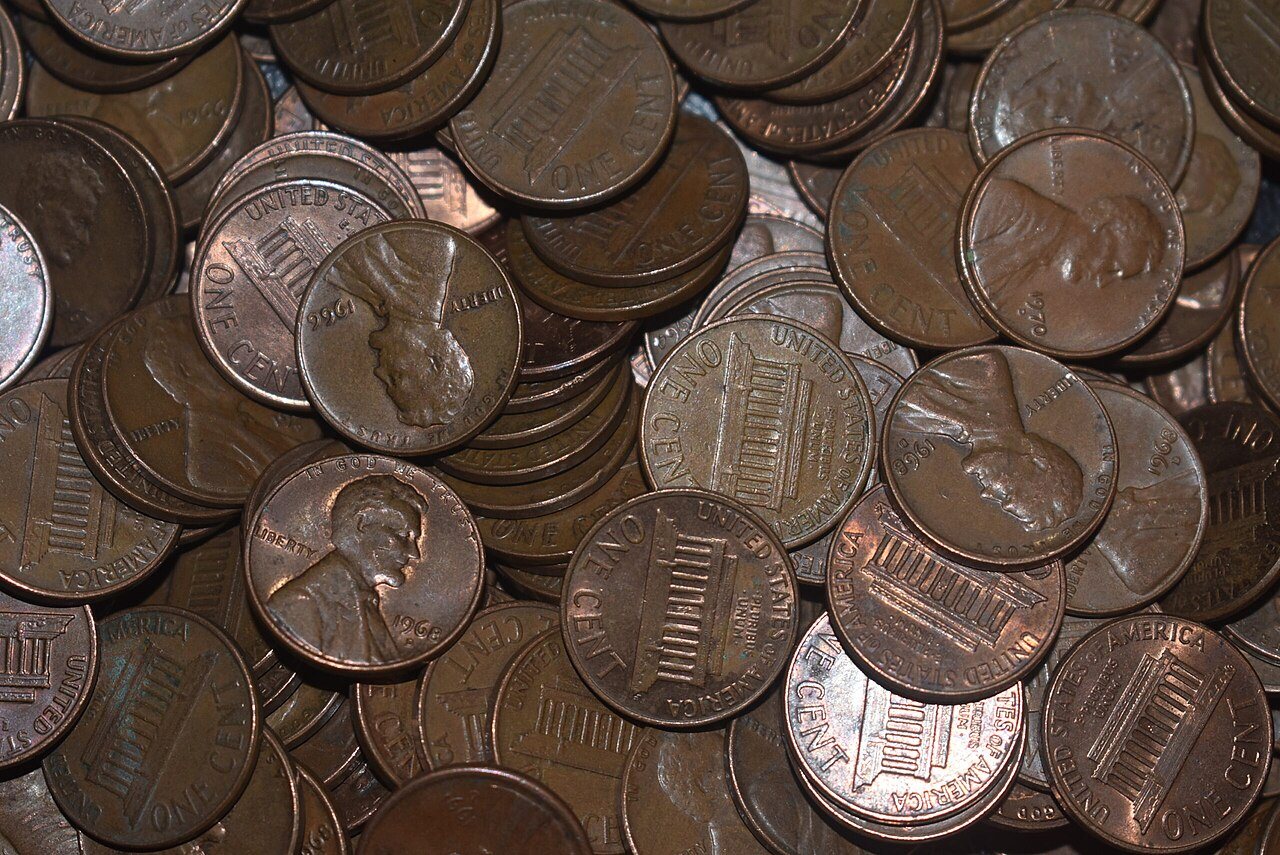 A pile of worn U.S. one-cent coins, some showing Lincoln's profile and others the Lincoln Memorial reverse